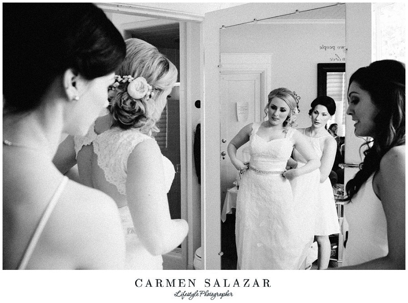 Bride puts on her wedding gown with help from bridesmaids