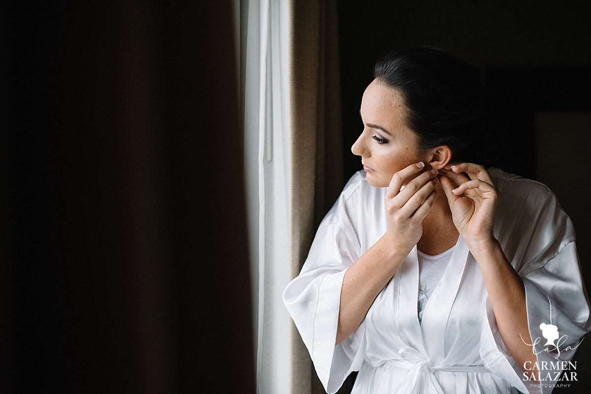 Glowing bride putting on jewelry - Carmen Salazar