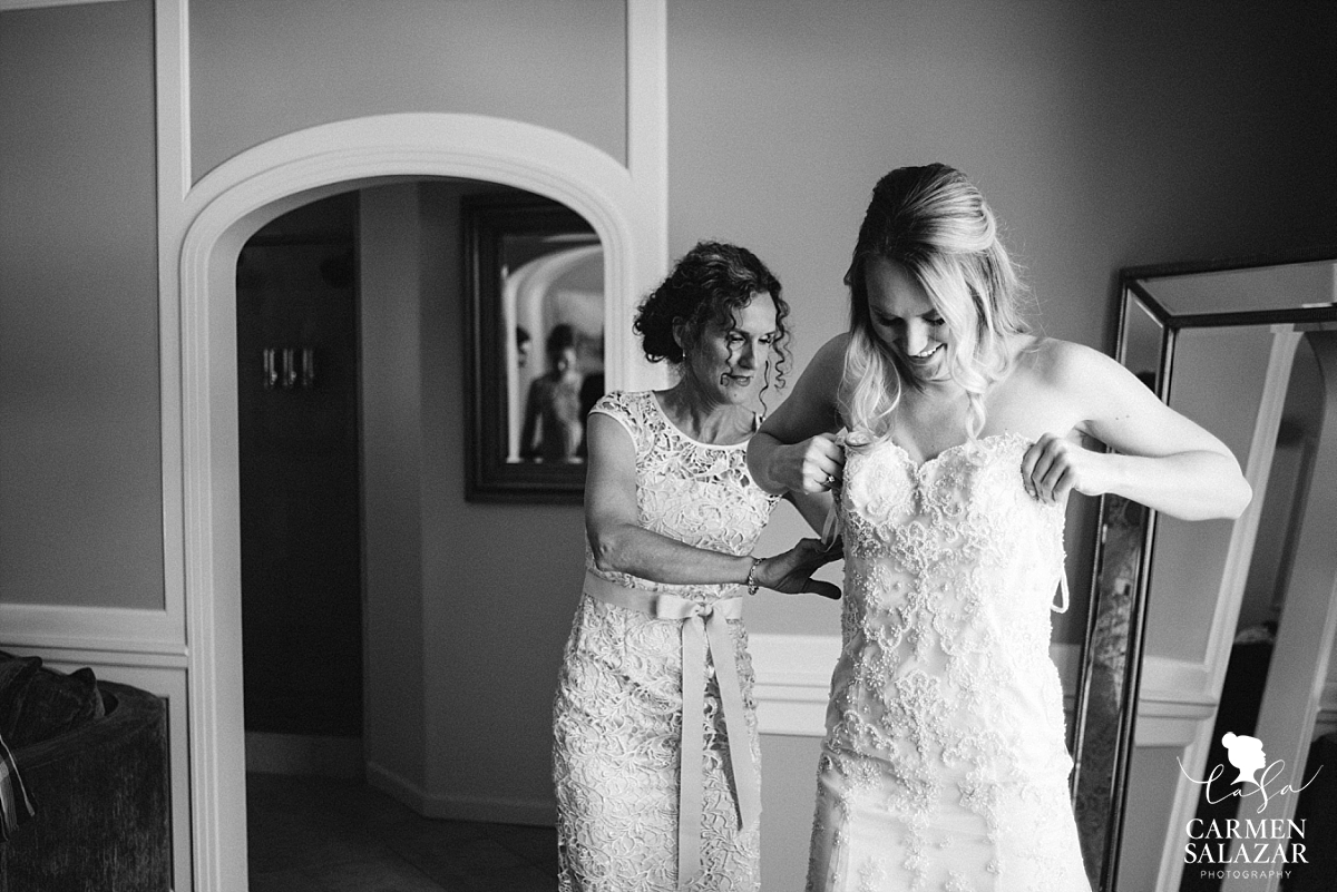 Mother helps bride put on gown - Carmen Salazar