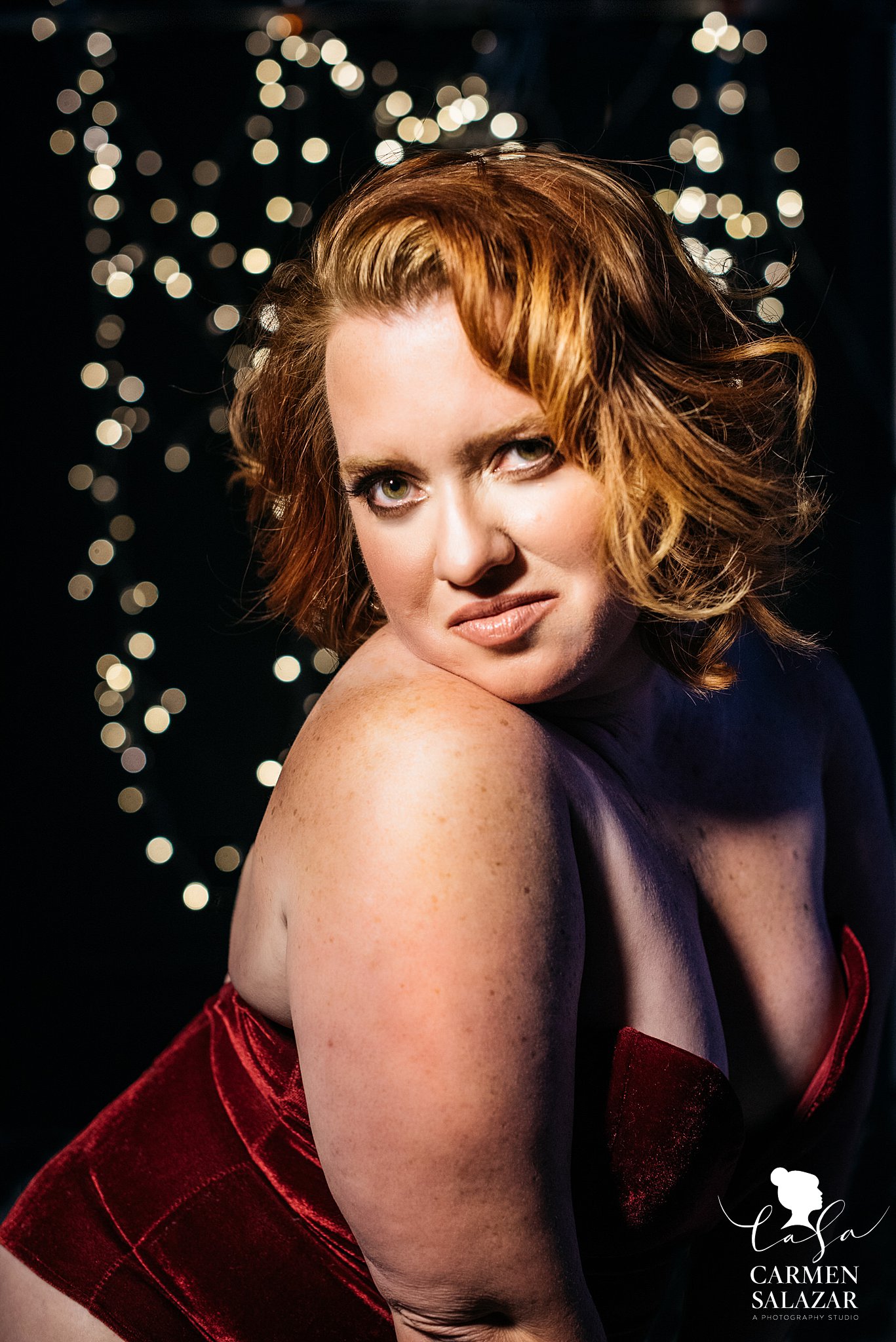 Boudoir portrait of a pin up redhead beauty with lights in the background 